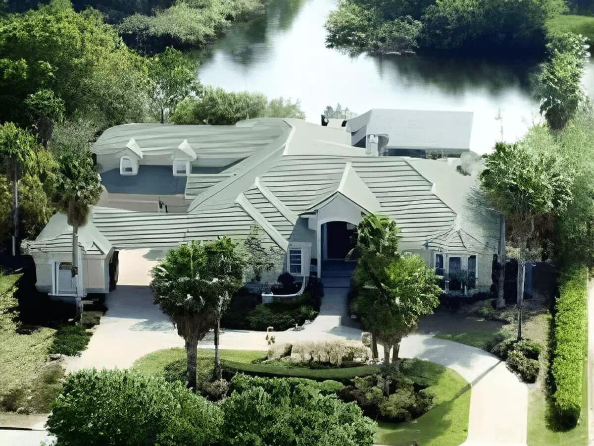 Aerial view of a luxury waterfront estate surrounded by palm trees with motor court and turnaround drive
