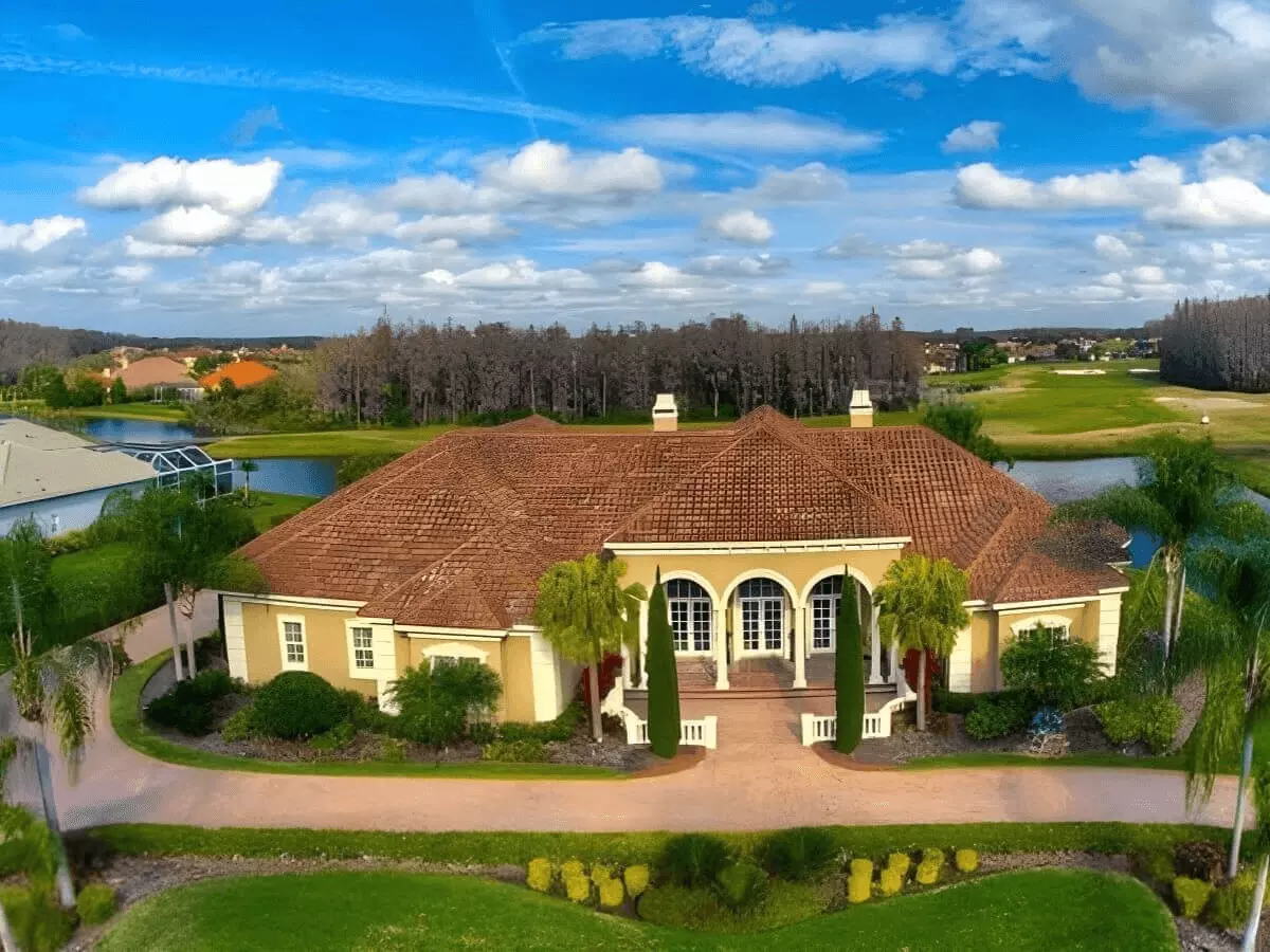 Aerial front view of a luxury home overlooking a lake and golf course