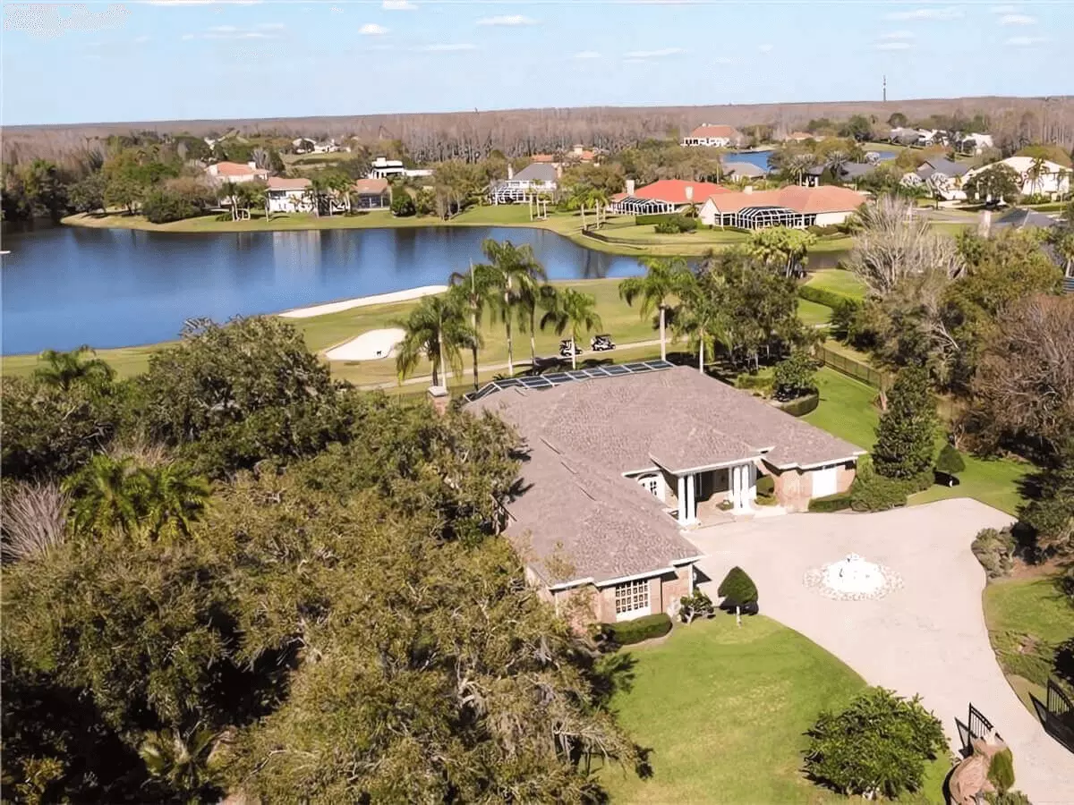 Aerial view of a luxury home with motor court in a golf course lake community