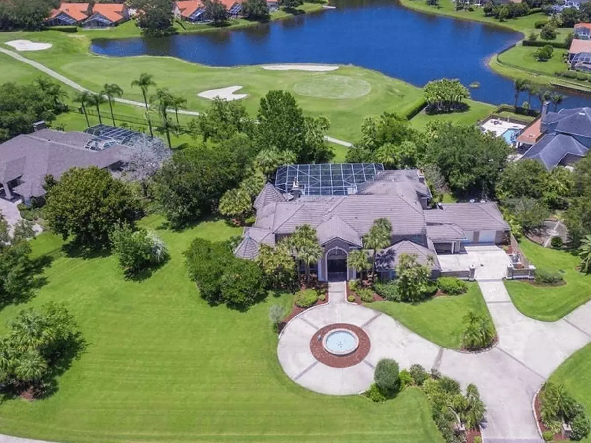 Aerial view of a fantastic luxury home with a motor court, screened pool backing to a golf course and a lake