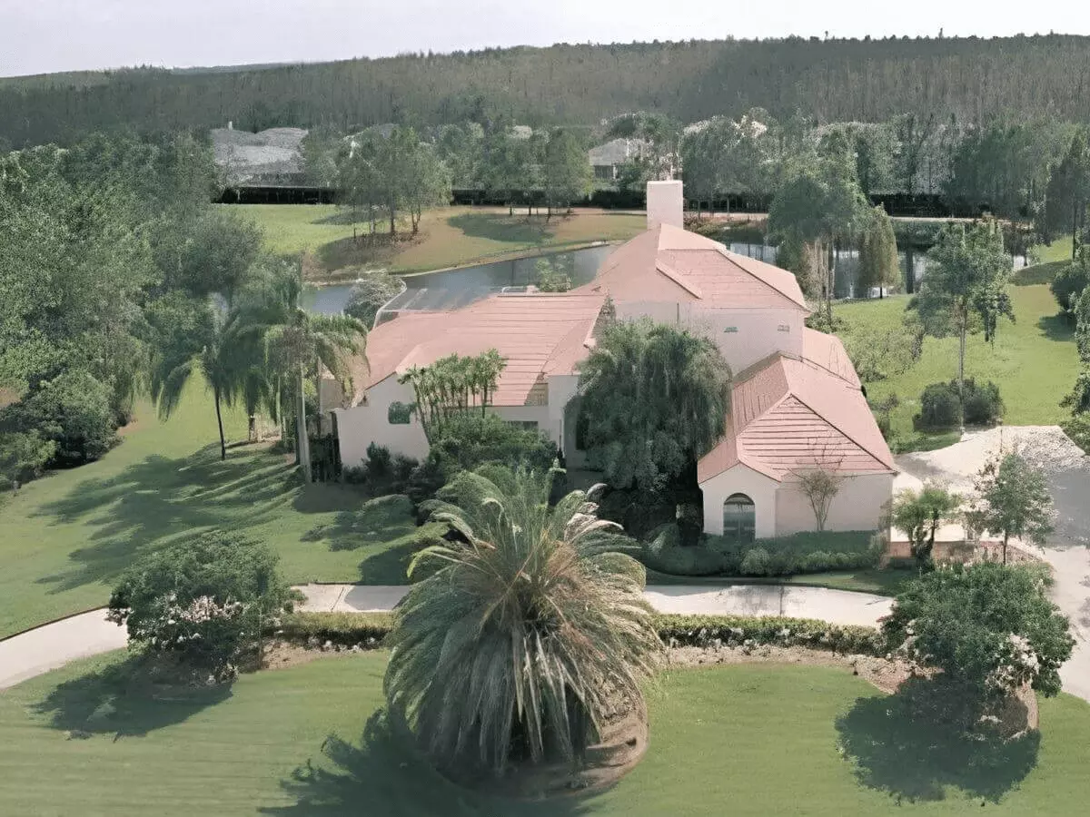 Ariel front view of a fantastic Mediterranean home with palms a huge pond on the golf course