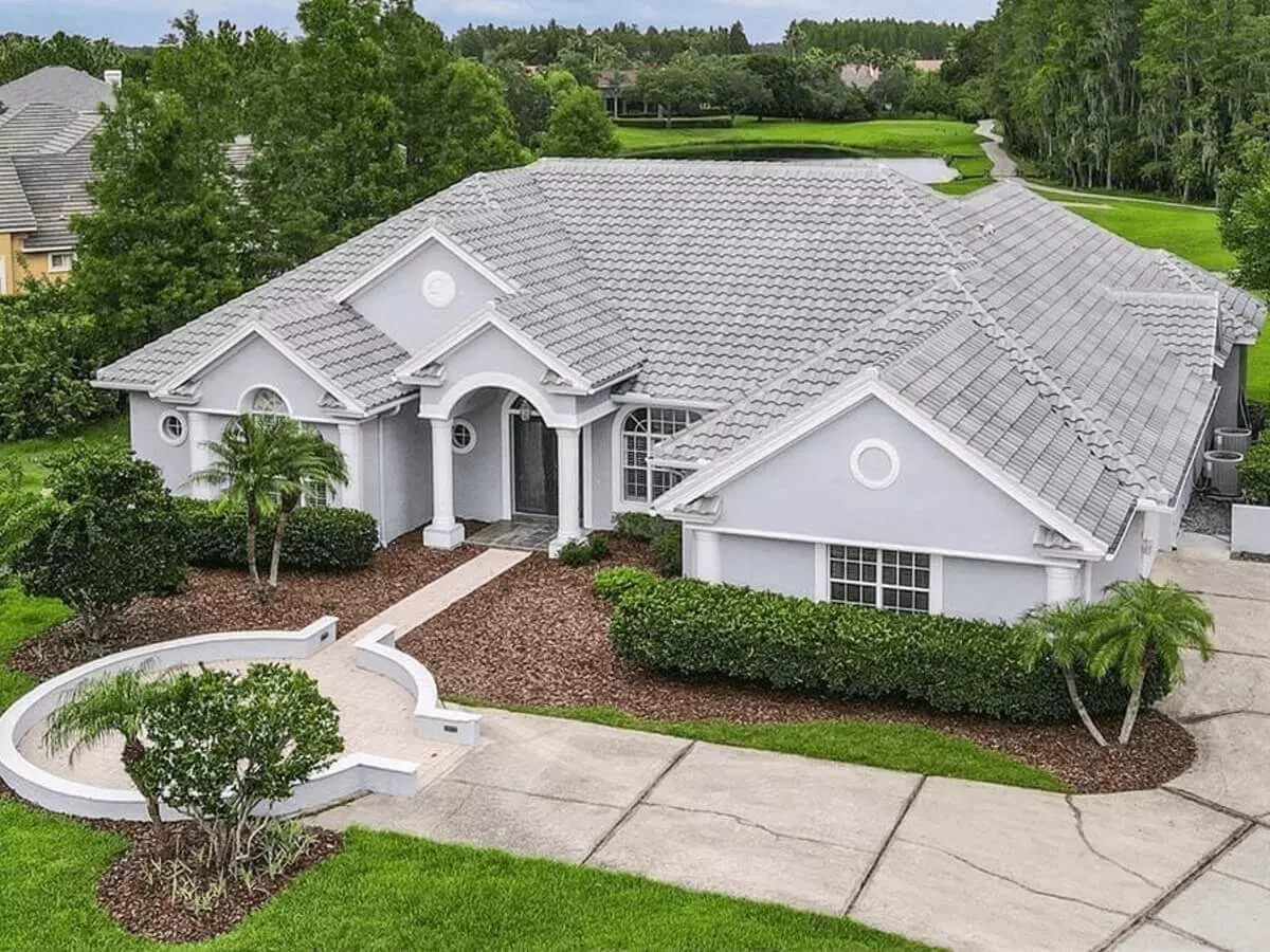 Front ariel view of a luxurious ranch with side drive and great landscaping on a golf course