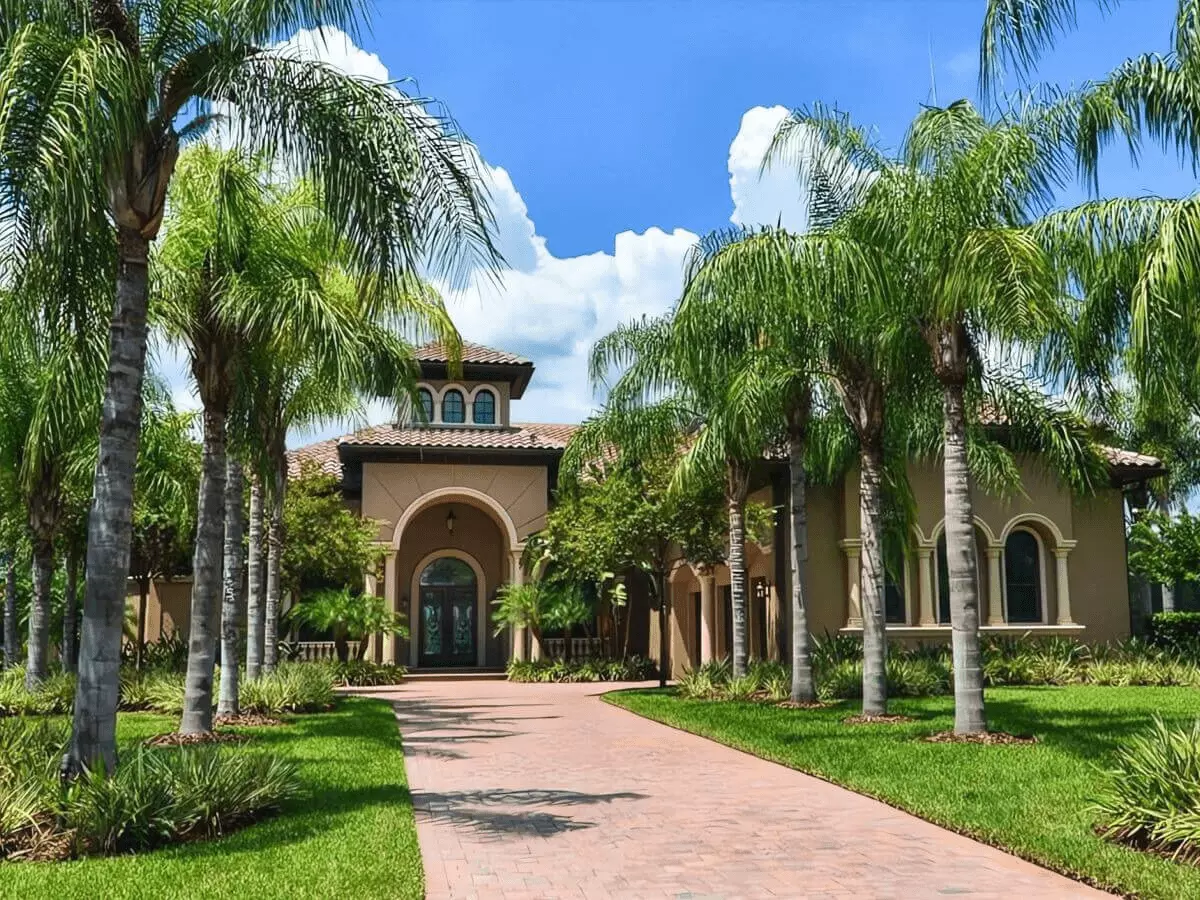 Front view of a Mediterranean Estate with brick paver motor court surrounded by mature palms