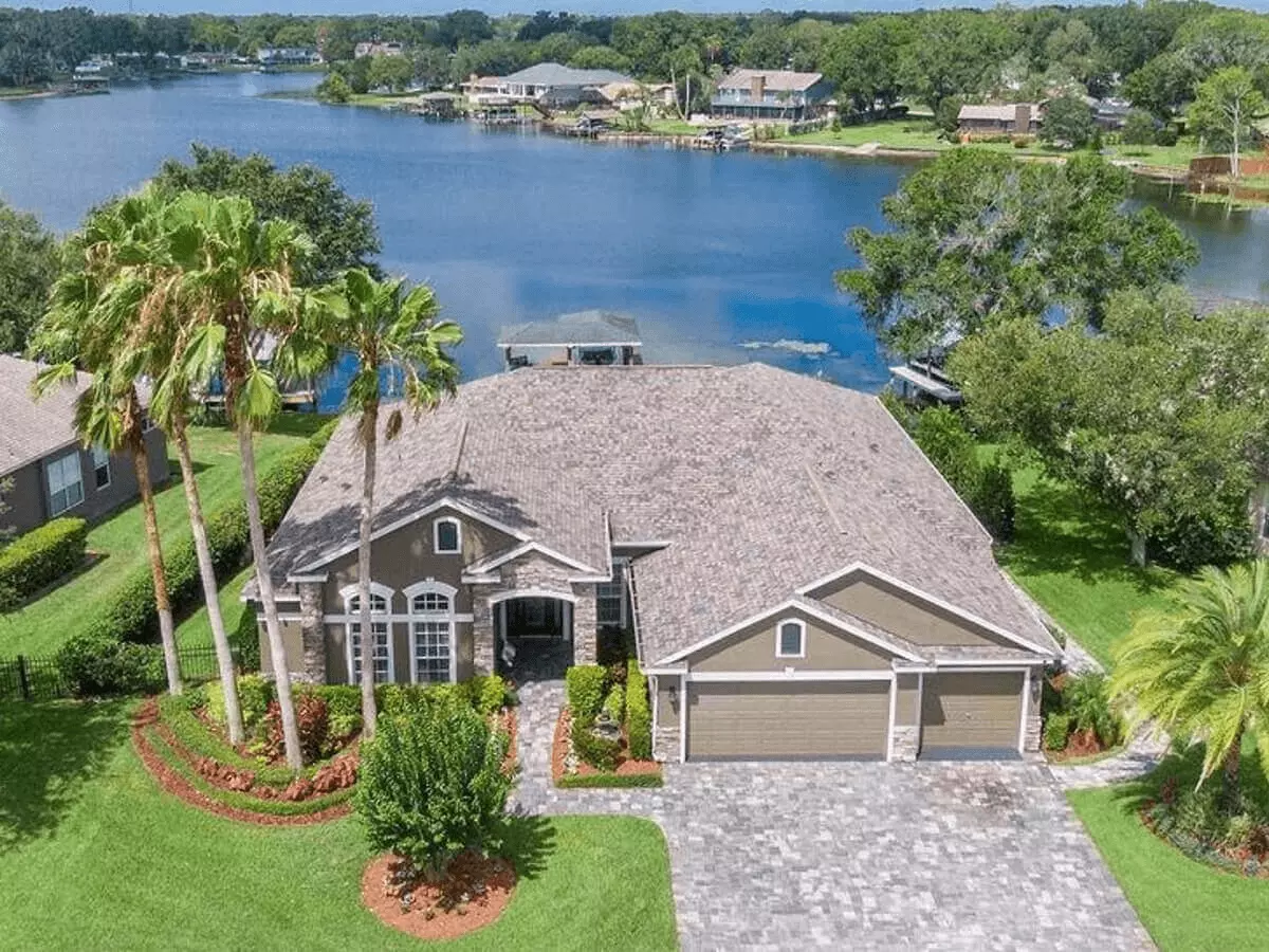 Ariel front view of a great ski lake Estate with towering palms and a boat doc